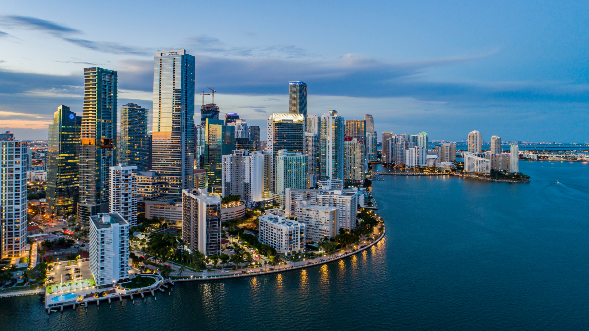 "Photo showing the iconic skyline of Brickell, Miami, featuring sleek and modern condominium towers against a backdrop of clear blue skies. The buildings exhibit contemporary architectural designs with glass facades and distinctive shapes, symbolizing urban sophistication and luxury living in the heart of Miami's financial district."